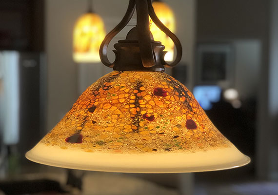 Stone chandelier and matching pendants over a dining table and breakfast bar.